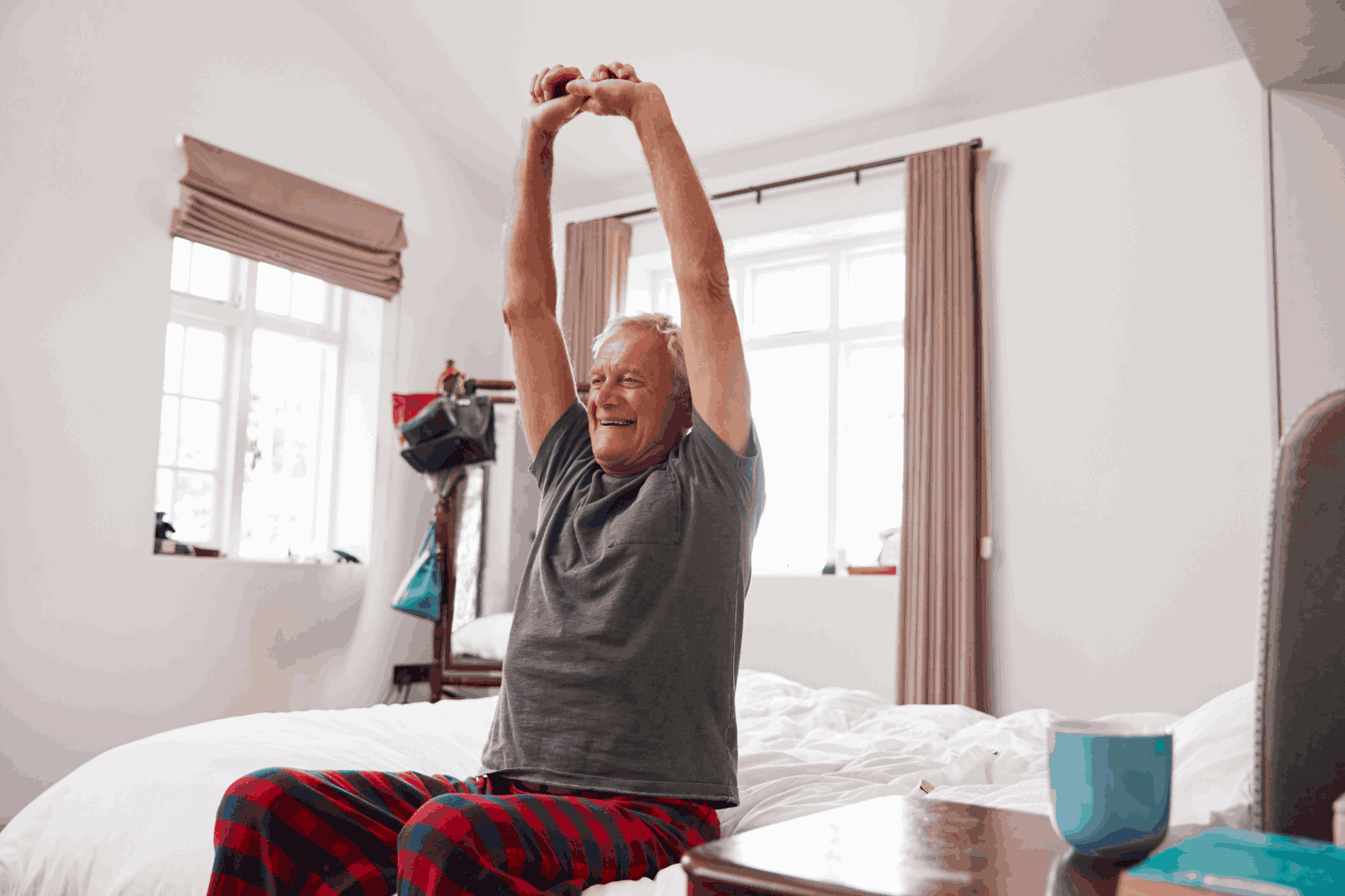 Senior stretching on the edge of his bed.