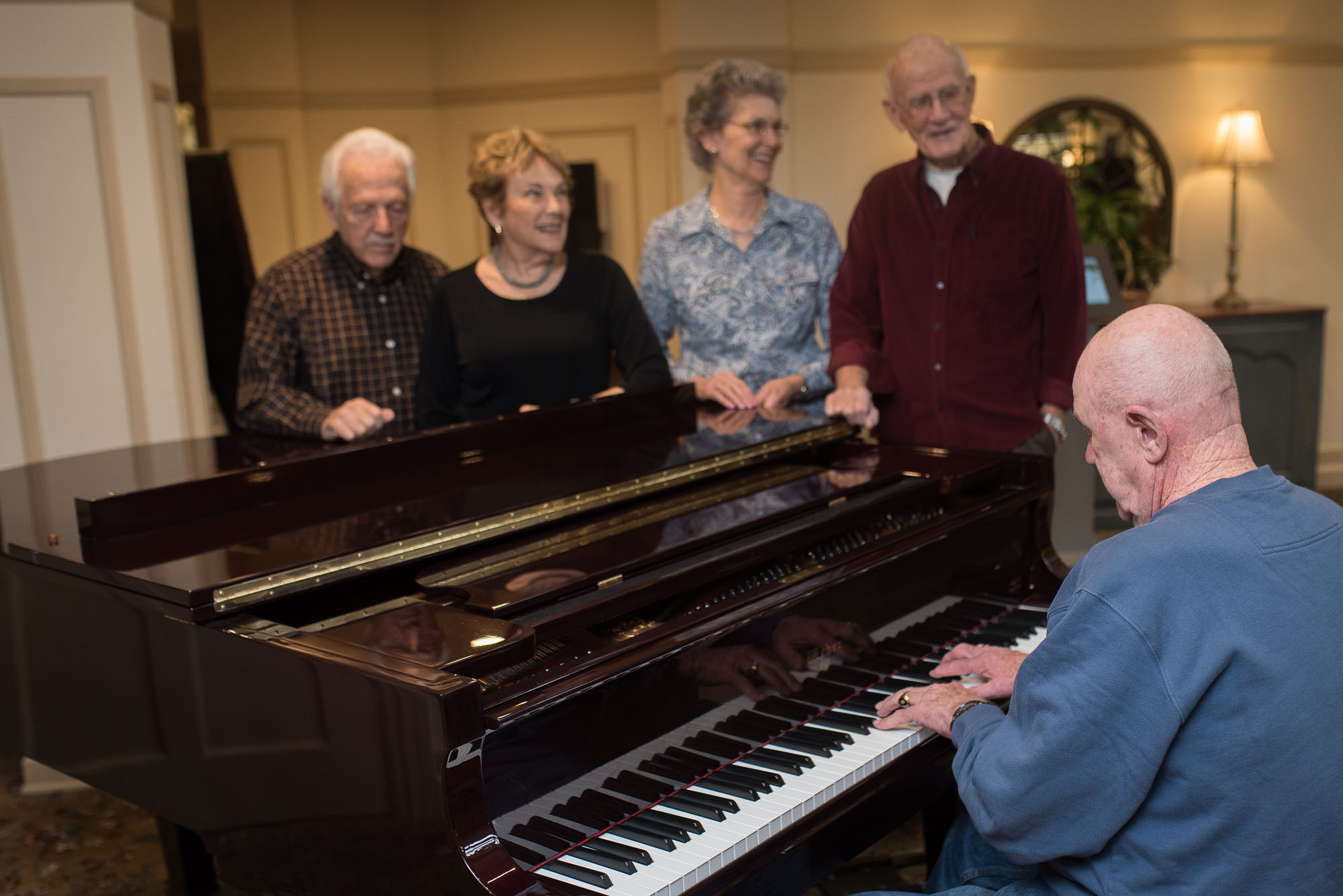 man playing piano to small group