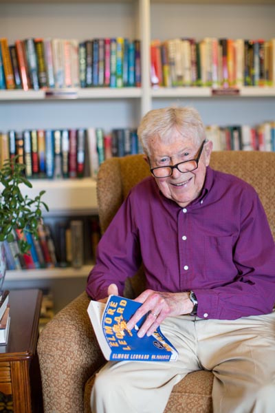 Resident holding a book in front of bookshelves 