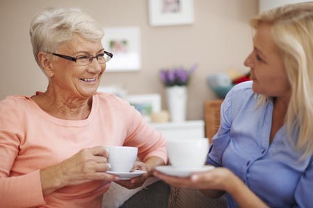 Two women talking holding tea cups