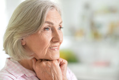 Woman with her hands under her chin smiling into the distance