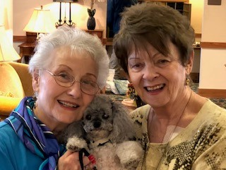 Two residents holding a dog between them