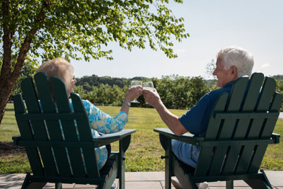 Senior Couple enjoying wine on the patio in Adirondack Chairs