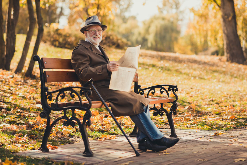 Senior reading paper on bench