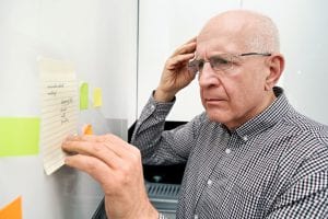 Elderly man with dementia looking at notes