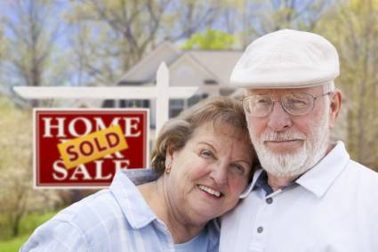 senior couple in front of sold house