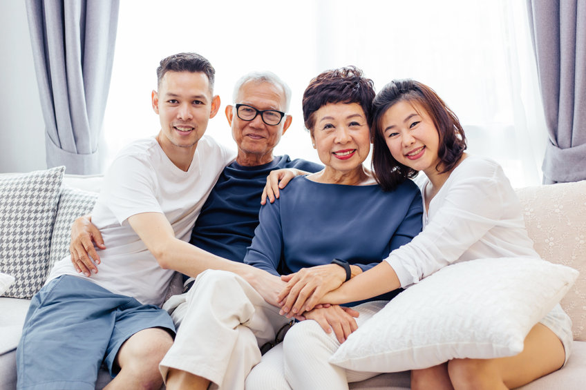 Asian family with adult children and senior parents relaxing on a sofa at home together