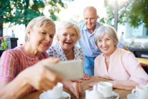 Group of seniors in an independent senior living community taking a selfie with a cell phone