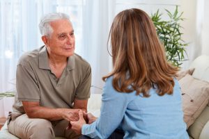 Elderly man talking and holding hands with adult daughter