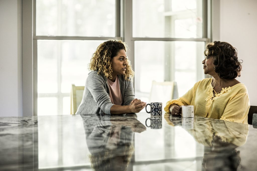 Senior woman and adult daughter talking in kitchen