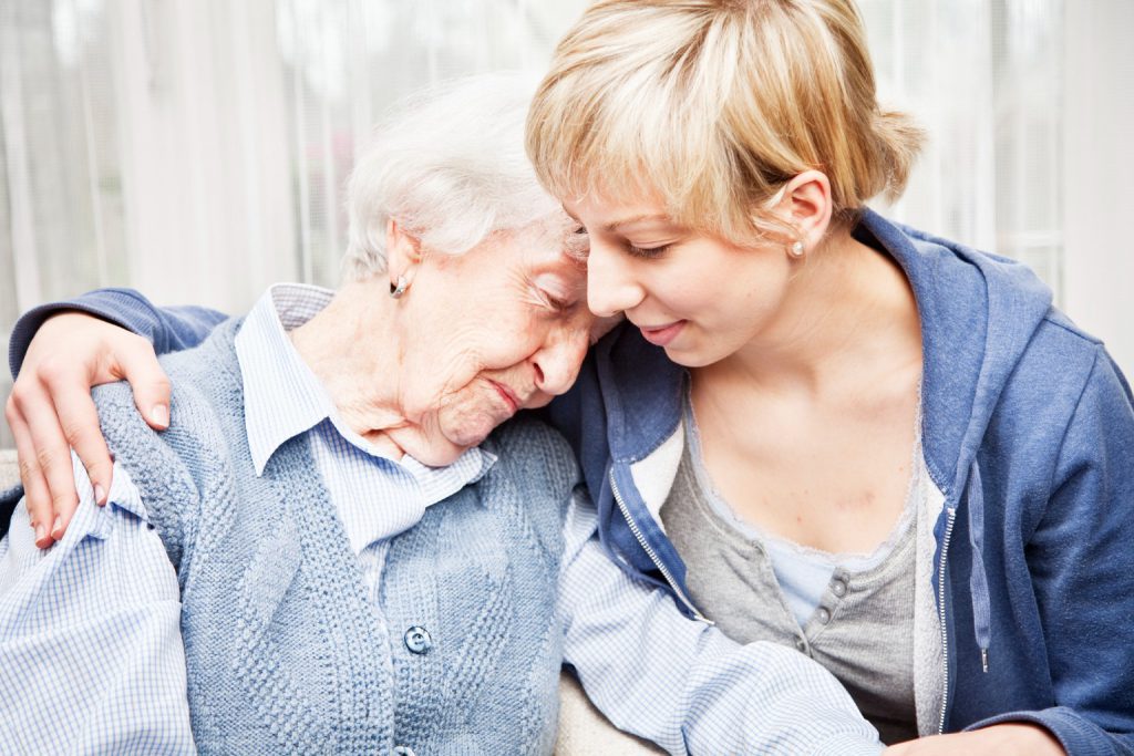 Young caregiver embracing elder woman