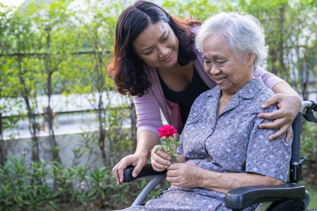 Woman with her hands on the shoulders of senior woman in wheelchair