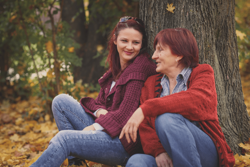 adult woman and senior woman talking beneath a tree